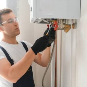 Professional plumber checking a boiler and pipes, boiler service concept.