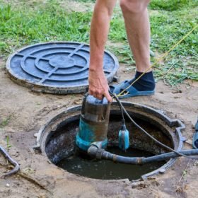 Septic tank maintenance, worker uses submersible waste water pump to pumping sewage out of tank.
