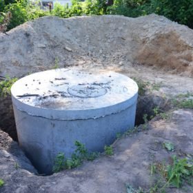 Manhole cover installation with sewer tank outdoors.